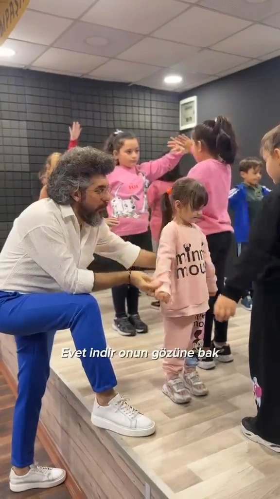 İlyas Çağlayan çocukların yanına eğilerek eşli bir yaratıcı drama çalışmasına eşlik ediyor